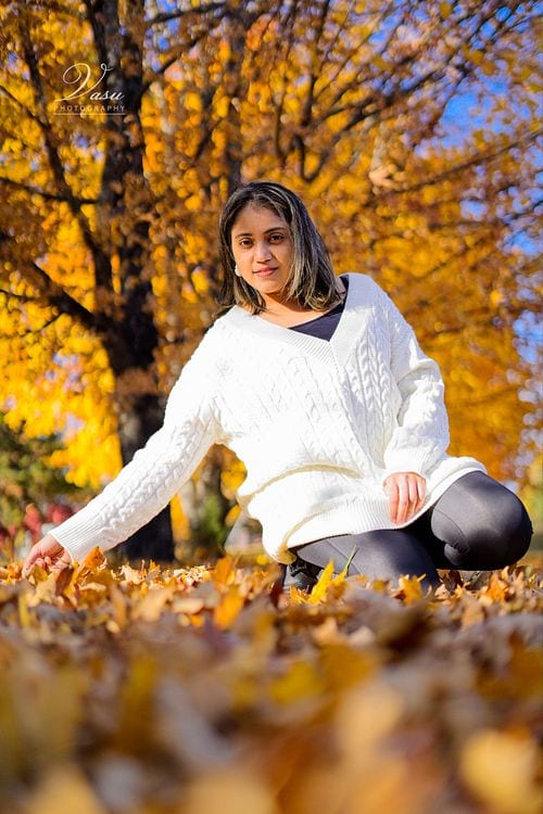 Woman seated among autumn leaves for an outdoor portrait