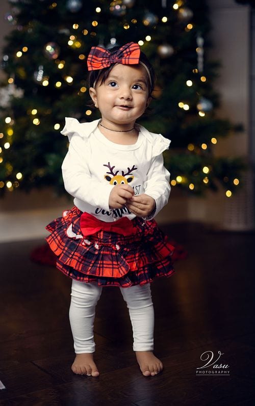 Young child looking up with curiosity beside softly lit holiday decorations