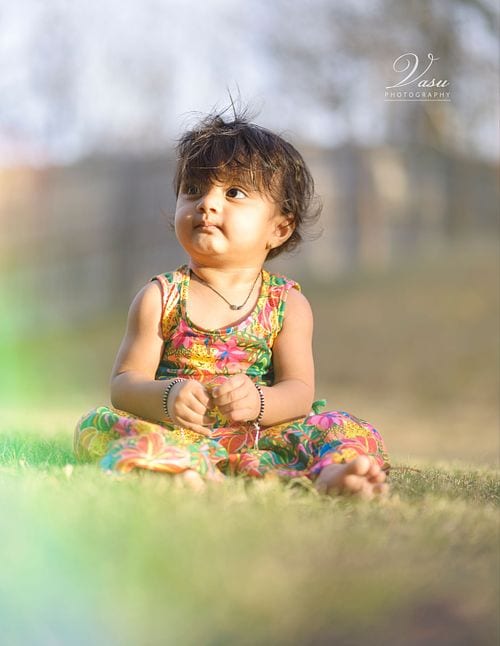 Young child seated in grass during an outdoor portrait