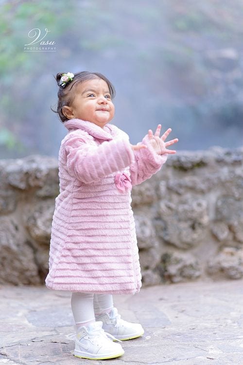Child smiling outdoors in a pink coat