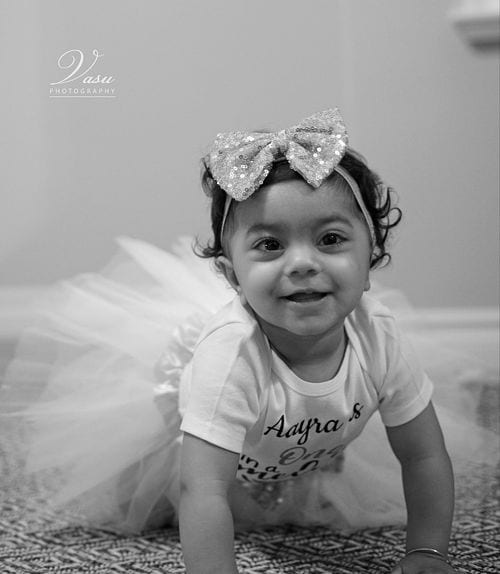 Black-and-white photograph of a smiling child crawling during a studio session