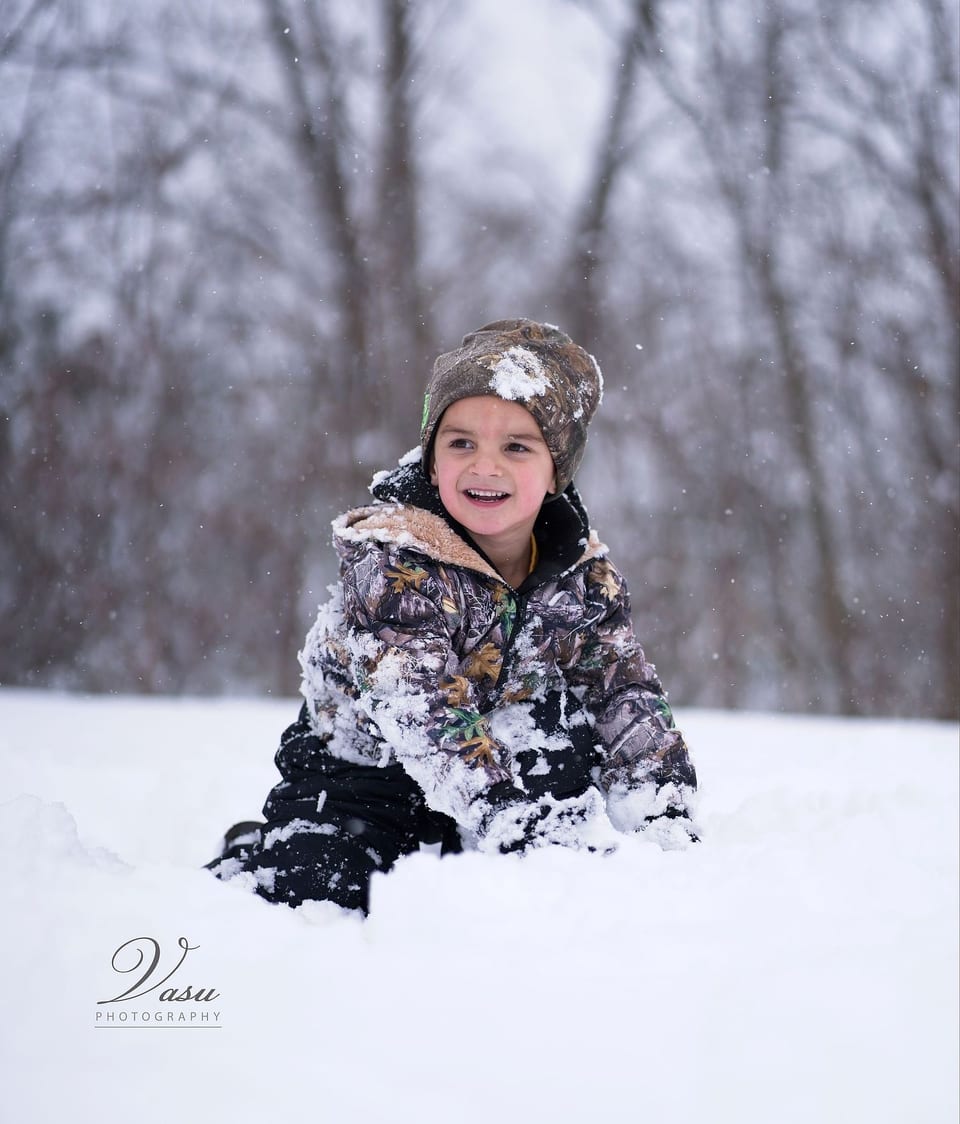 Child laughing while playing in freshly fallen snow