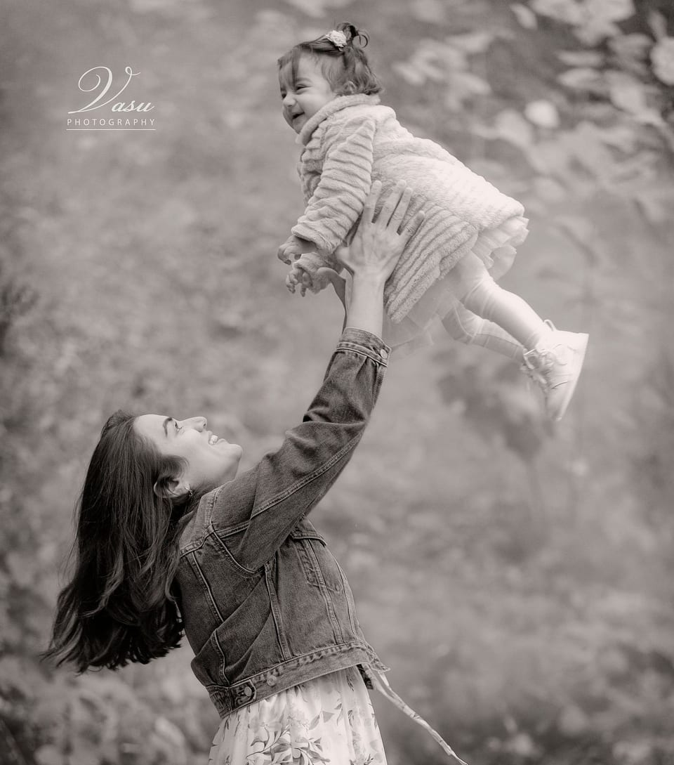 Mother lifting her smiling baby during a candid outdoor portrait