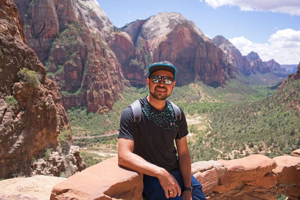 Vasu outdoors while traveling with a mountain landscape behind him