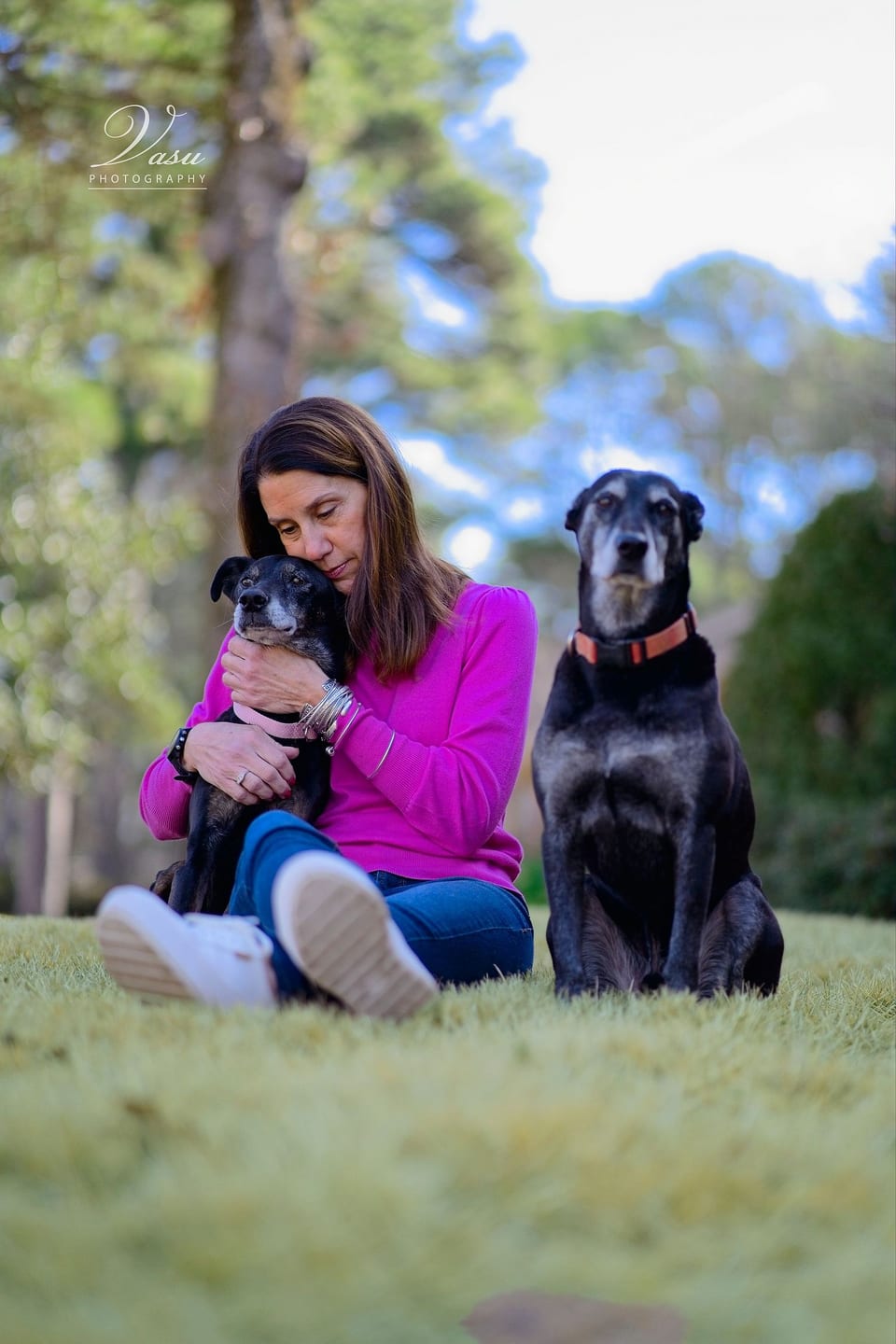 Woman seated outdoors with two dogs during an on-location portrait